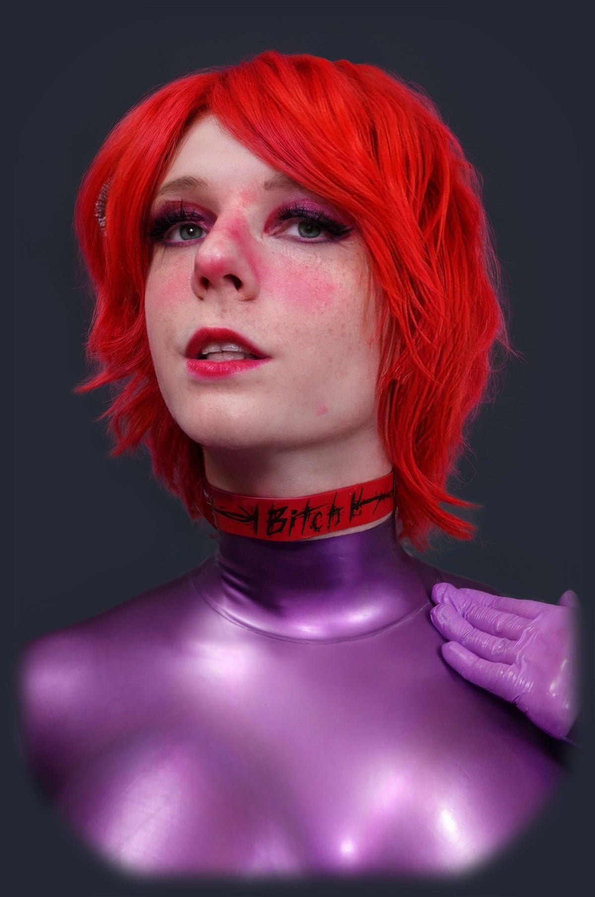 Red latex collar worn with a purple catsuit, side view