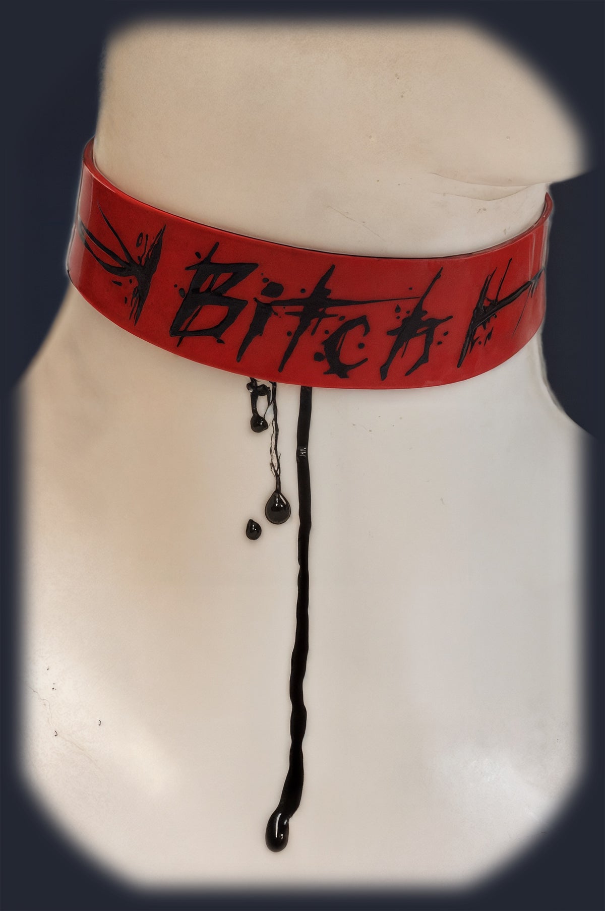 Red latex collar with a custom "Bitch" painted design, close-up