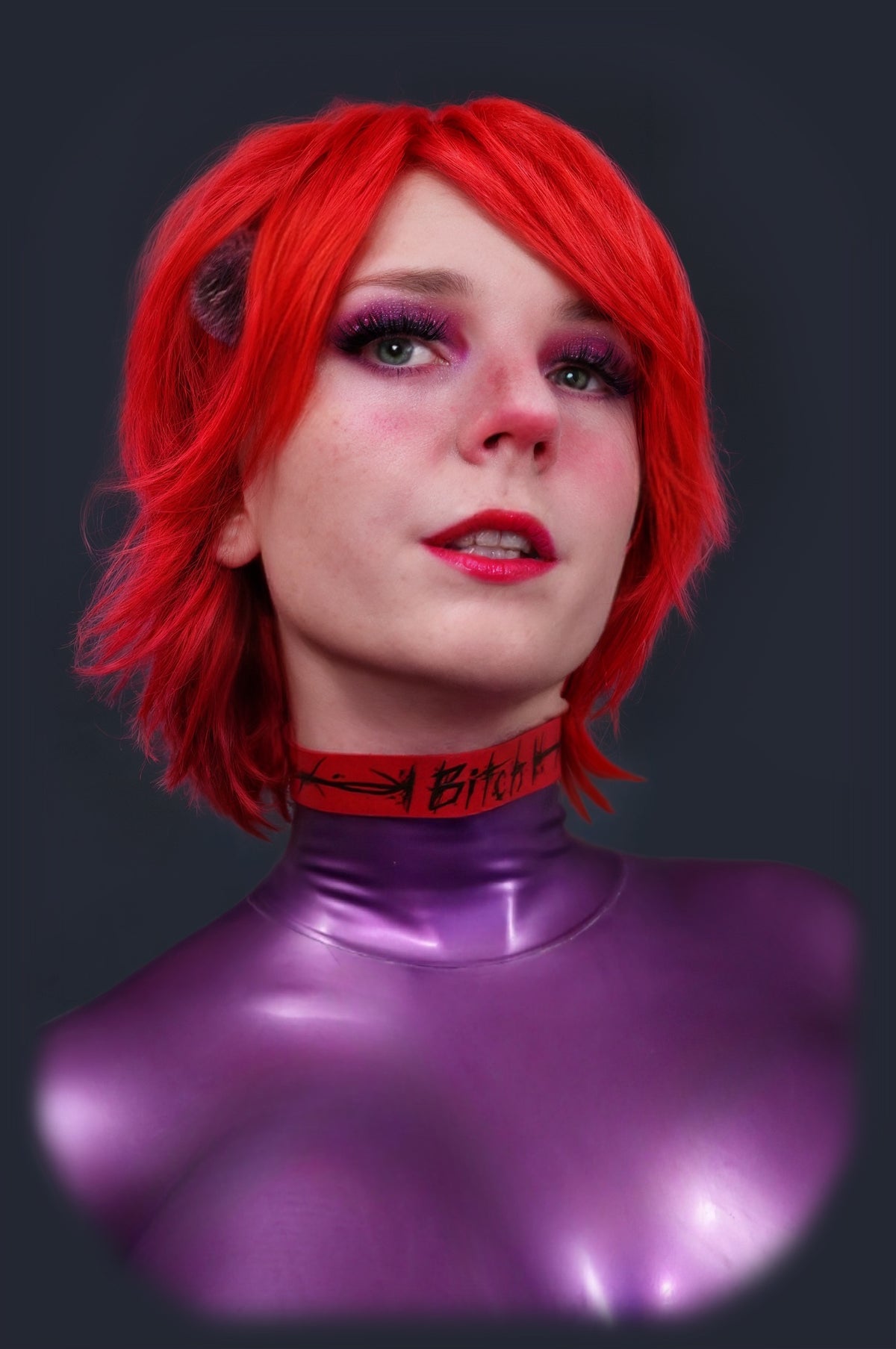 Red latex choker worn with a purple latex catsuit, front view